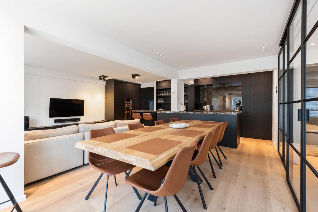 a dining room and kitchen with a wooden table and chairs at Hyper-Luxeappartement, zeezicht, centrum, airco, optie hotelservices in Ostend