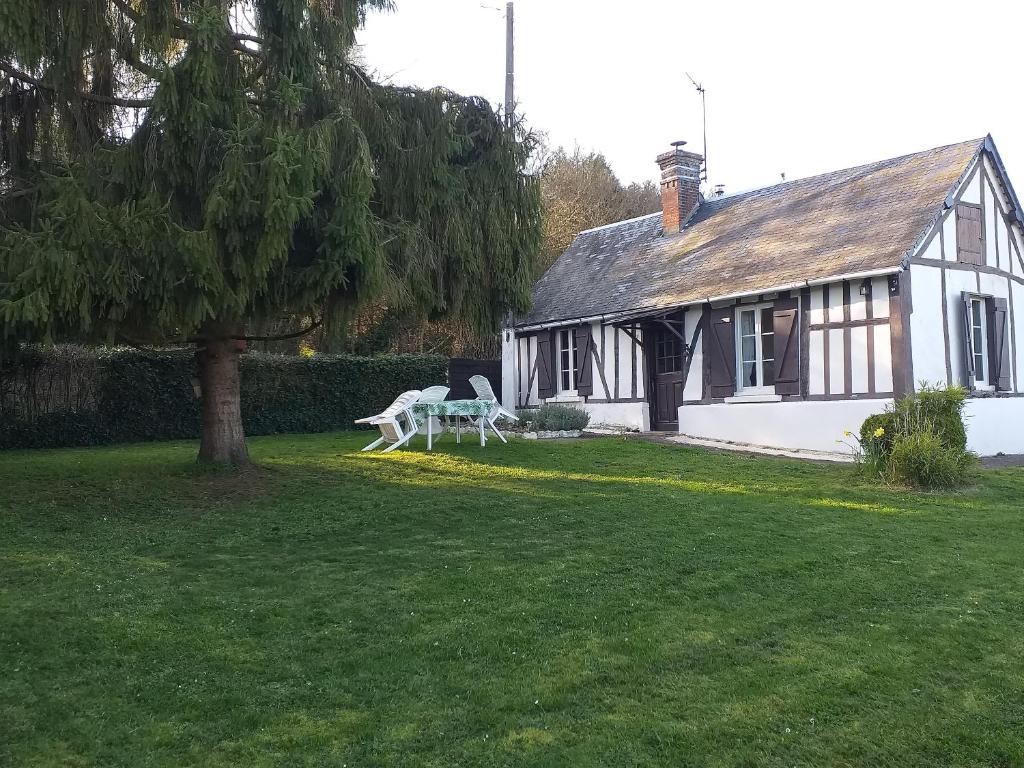 a house with a table and chairs in a yard at La petite maison normande in Ticheville