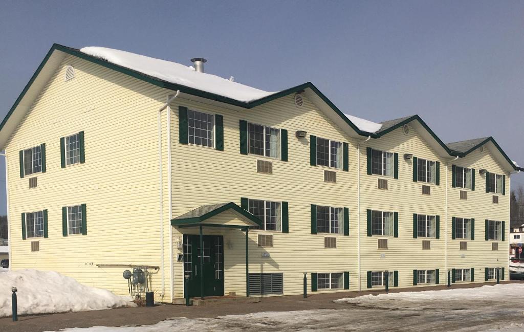 un gran edificio blanco con techo negro en Almada Inn, en Fort Nelson