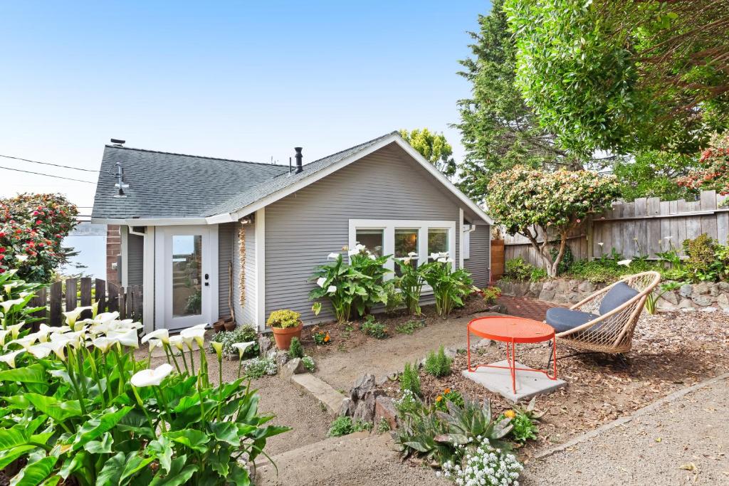 a garden with a red table and chairs in front of a house at Surfer's Paradise in Bodega Bay