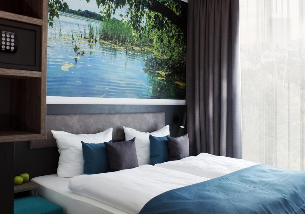 1 dormitorio con 1 cama y una pintura de un lago en Hotel Amper en Germering