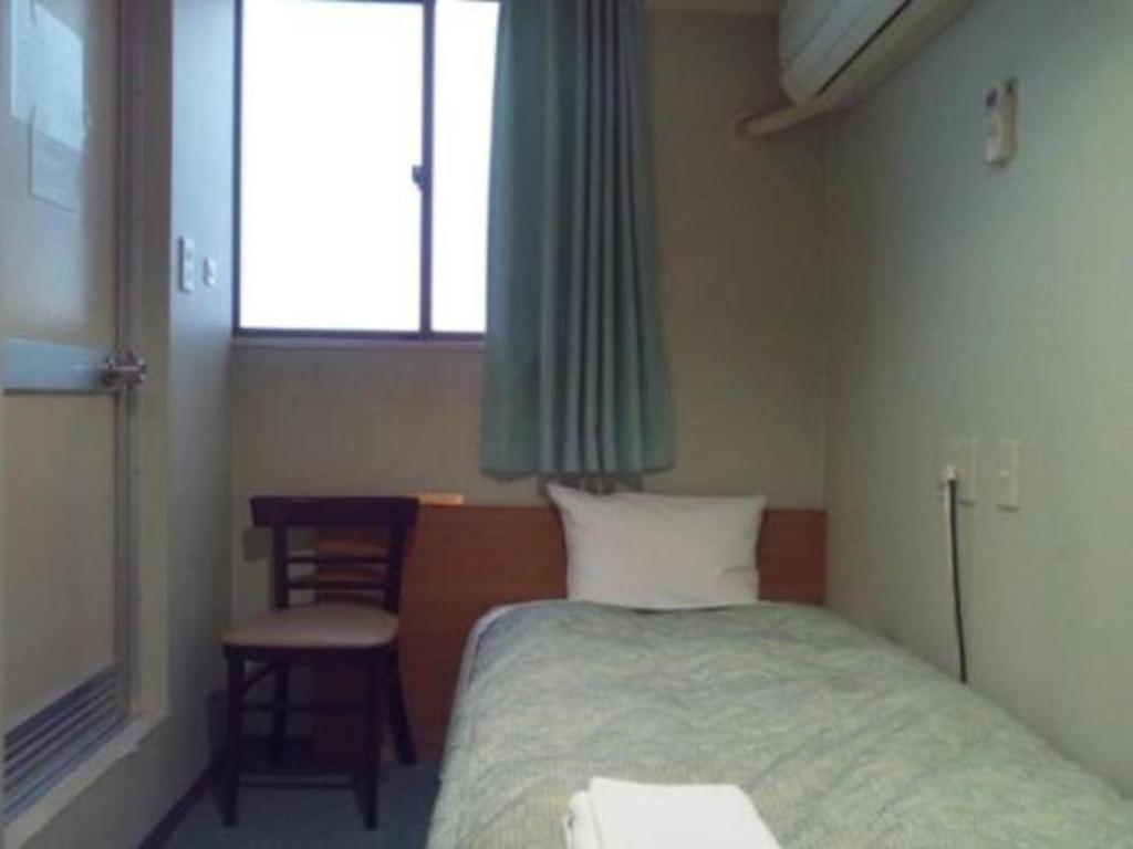 sypialnia z łóżkiem, krzesłem i oknem w obiekcie City Inn Nishi Tanabe / Vacation STAY 78427 w Osace