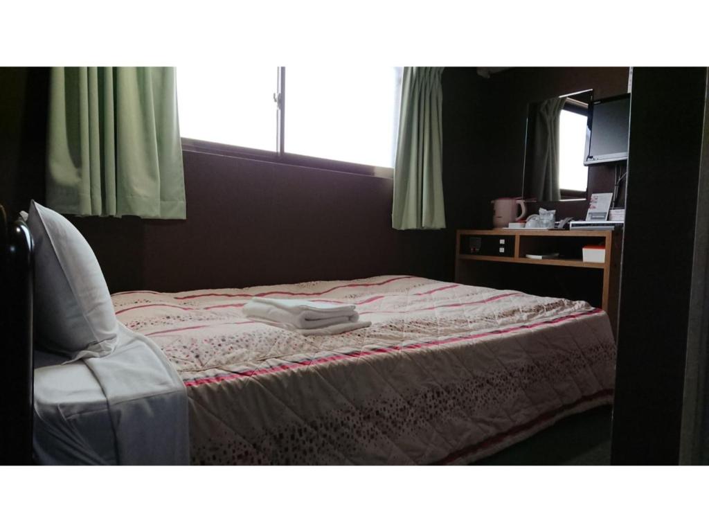 een slaapkamer met een bed met een stoel en een spiegel bij City Inn Nishi Tanabe / Vacation STAY 78535 in Osaka