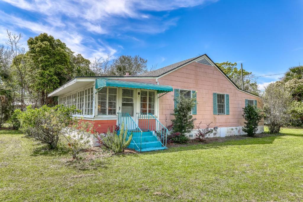 a pink house with a porch and a yard at Beach Cottage on Jones in Tybee Island