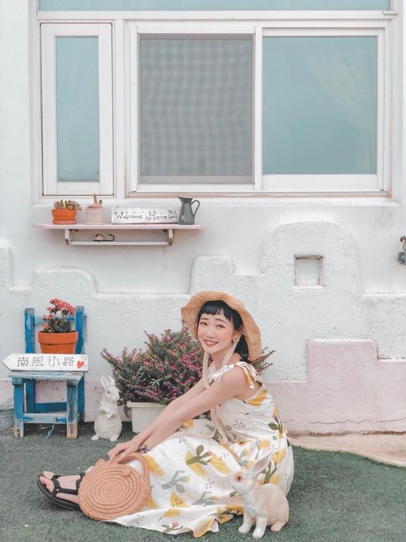 a woman sitting on the ground in front of a house at Minami Kaze in Magong