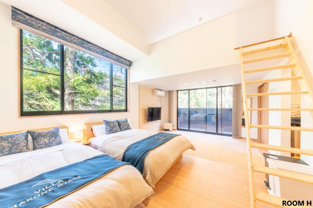 Duas camas num quarto com janelas e uma escada em VILLA HAKONE STAGE em Hakone