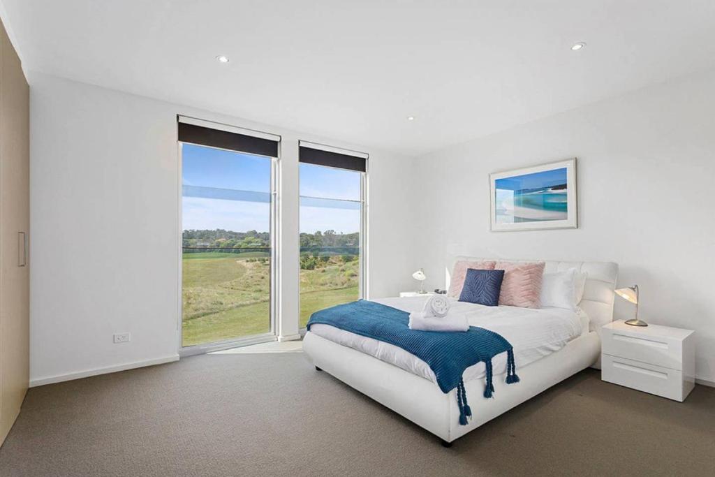 Dormitorio blanco con cama y ventana grande en DREW Golfers Delight close to St Andrews Beach, en Fingal