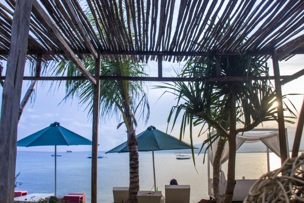 vistas a la playa con sombrillas y palmeras en Kaluku Gili Resort, en Gili Air