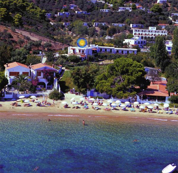 a beach with umbrellas and people in the water at Vontzos Hotel in Achladies