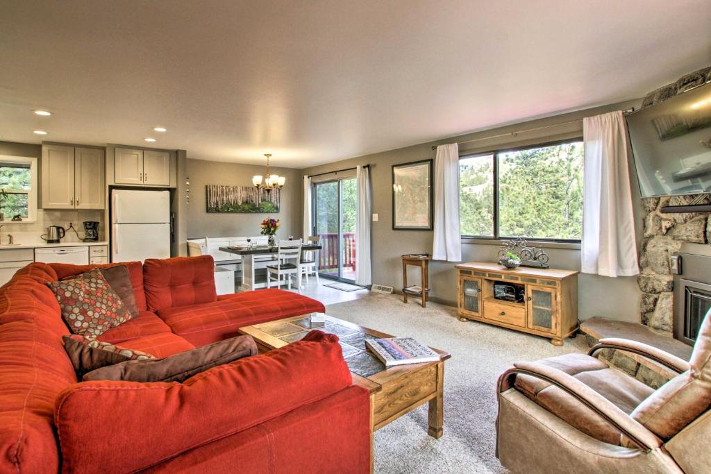 a living room with a red couch and a kitchen at Luxe Updated Home with Grill and Hot Tub 4 Mi to RMNP in Estes Park