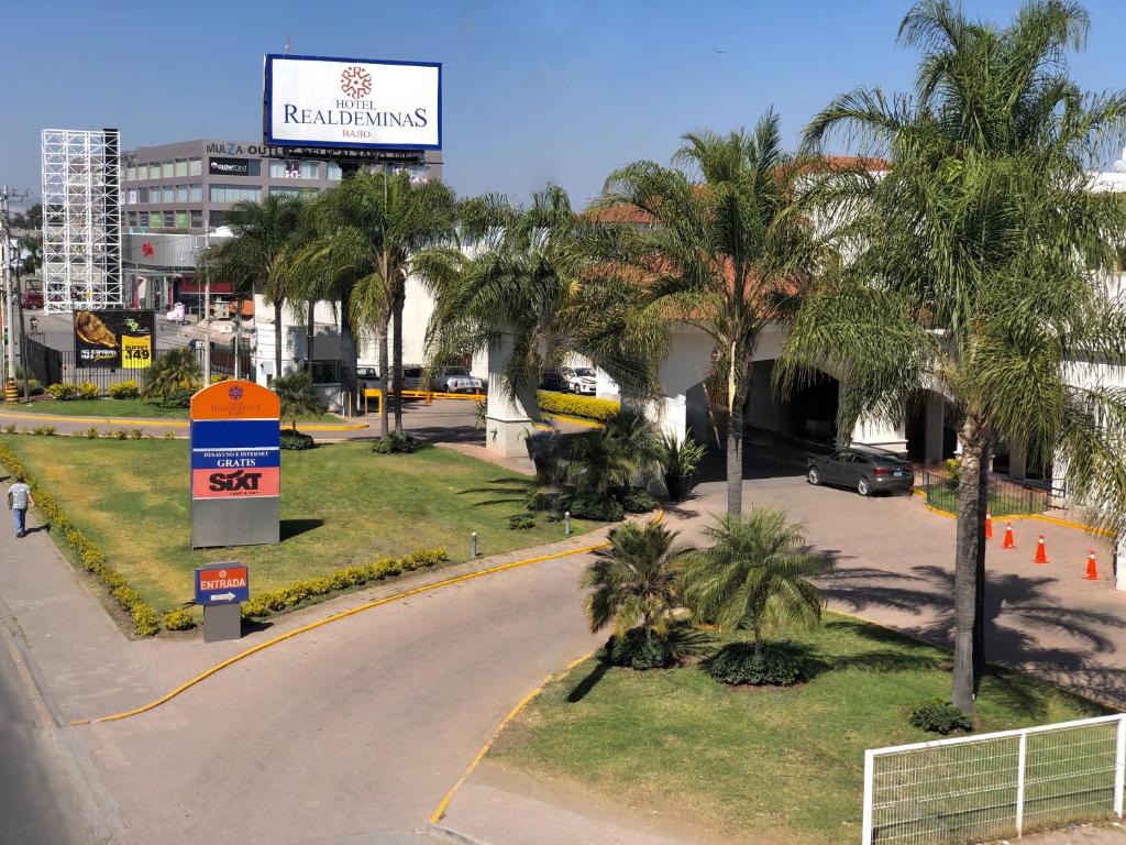 une rue dans une ville avec des palmiers et un panneau dans l'établissement Hotel Real de Minas Bajio, à León