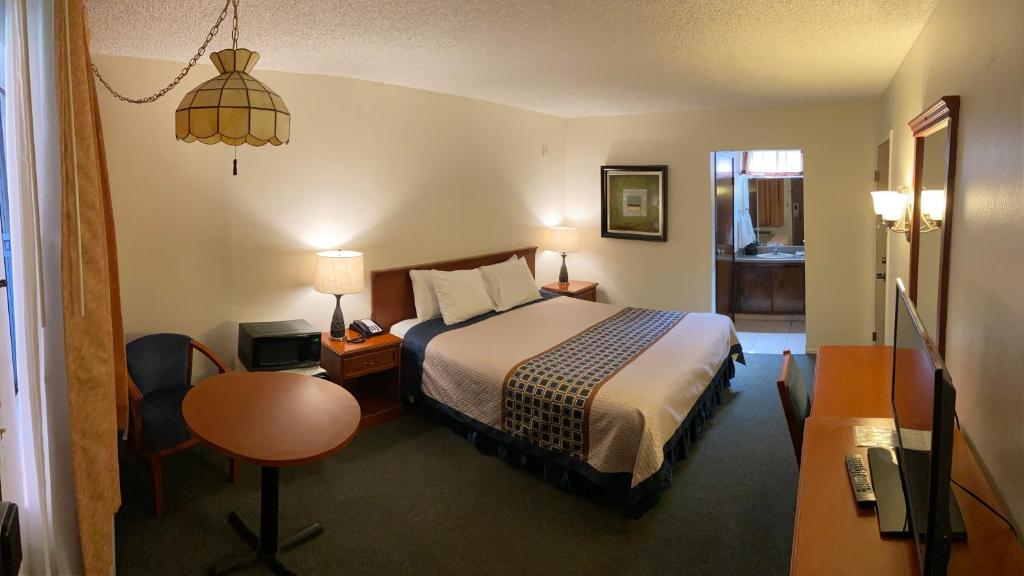 a hotel room with a bed and a desk and a table at Vantage Point Inn - Woodland Hills in Woodland Hills