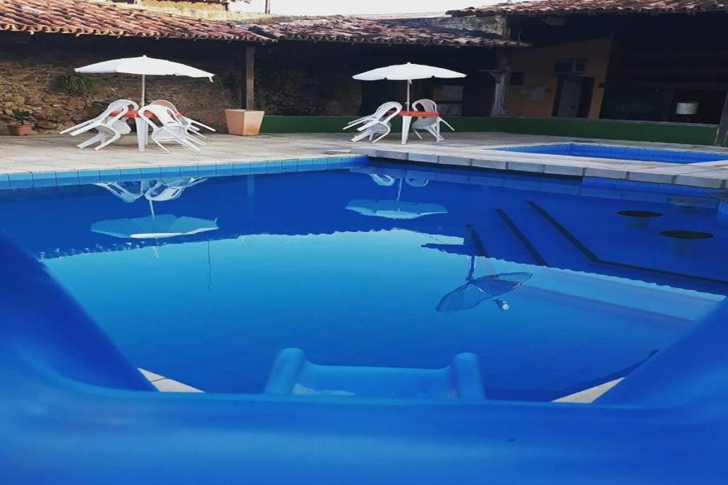 two chairs and umbrellas in a swimming pool at Hotel Recanto Do Sol in Porto Seguro