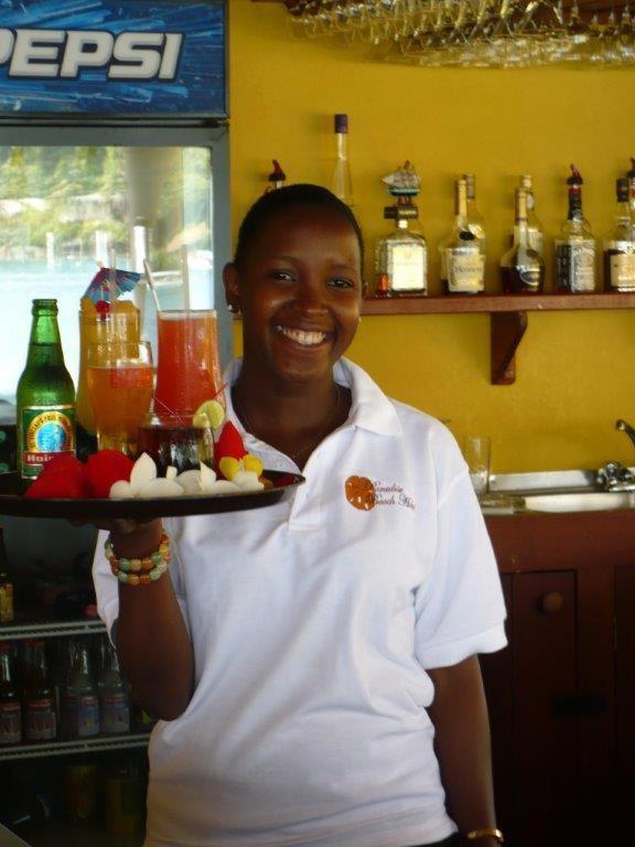a woman holding a tray of food and drinks at Paradise Beach Hotel in Kingstown