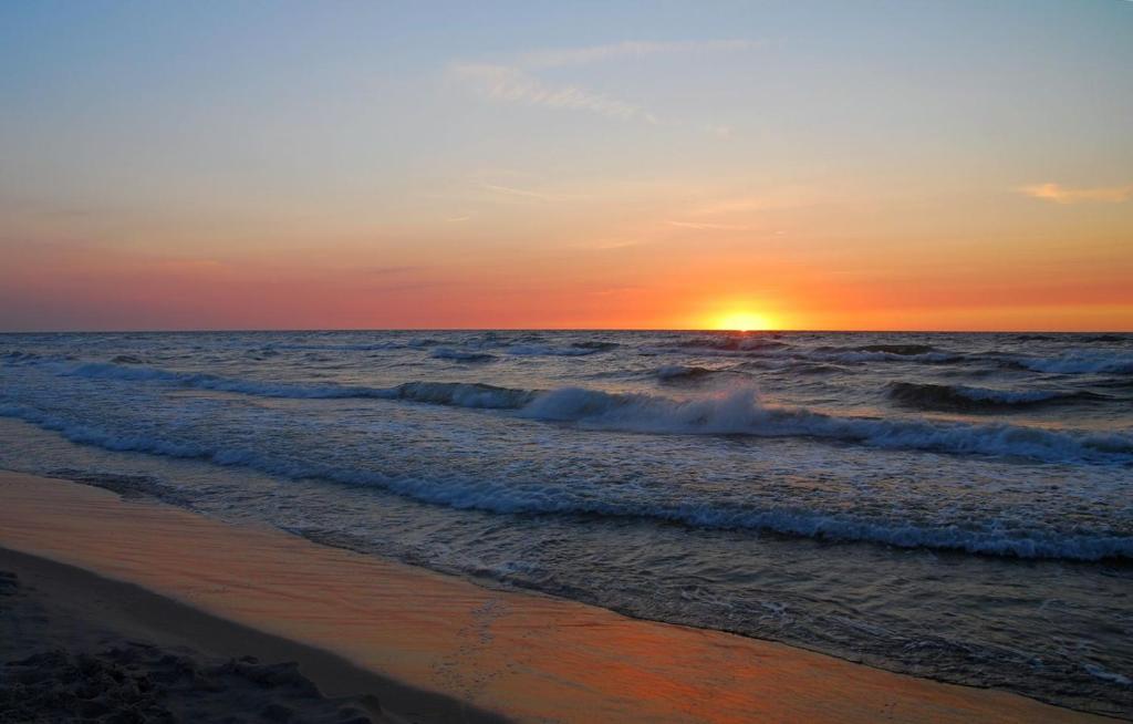 a sunset on the beach with the ocean at Willa Do-Dar in Krynica Morska