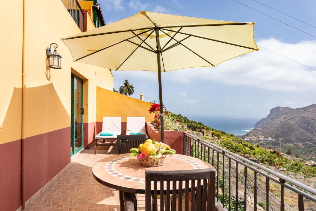 - une table avec un parasol sur un balcon donnant sur l'océan dans l'établissement Home2Book Stunning View La Era de Hermigua & Wifi, à Hermigua