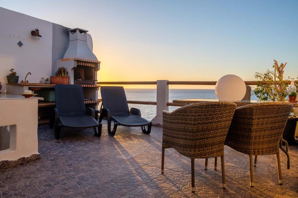 un patio con sillas y una mesa con vistas al océano en Luminous loft apartment next to the Atlantic Ocean, en Radazul