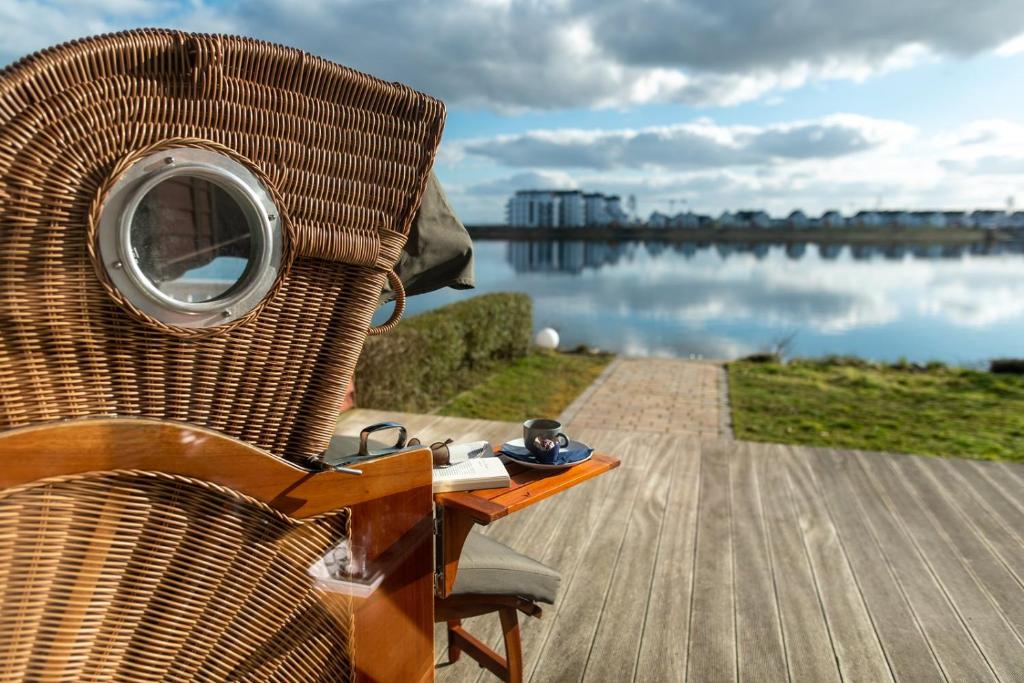 a wicker chair sitting next to a body of water at Hus im Lee un Luv in Olpenitz