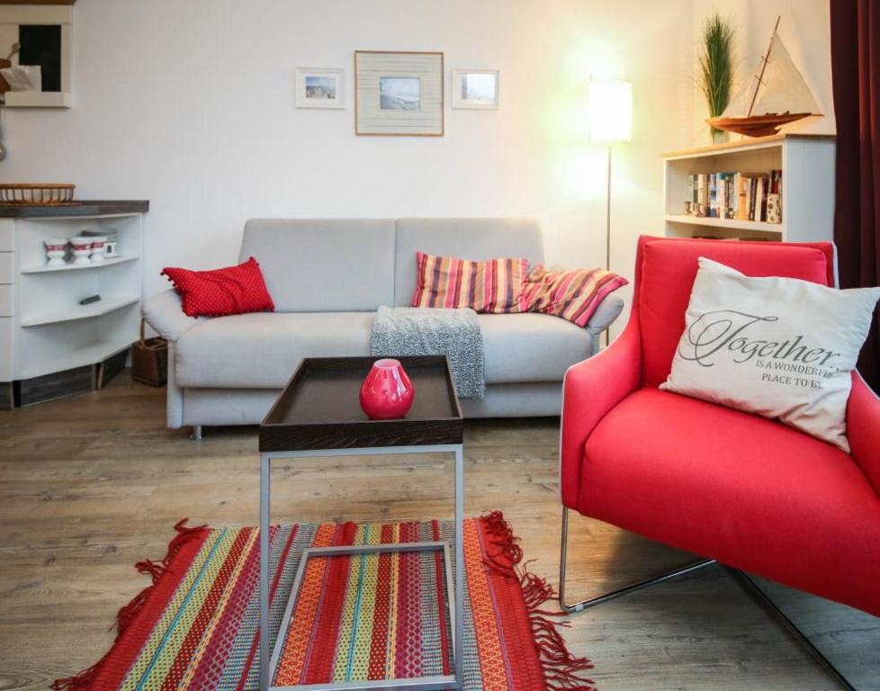 シャルボイツにあるFerienwohnung Stranddüne 2のリビングルーム(ソファ、赤い椅子付)