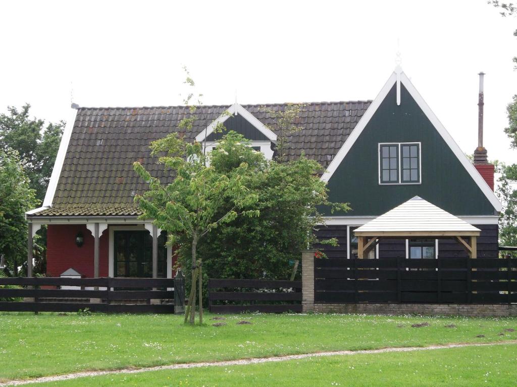 a house with a fence in front of it at Nicely decorated villa with garden, near the sea in Hippolytushoef