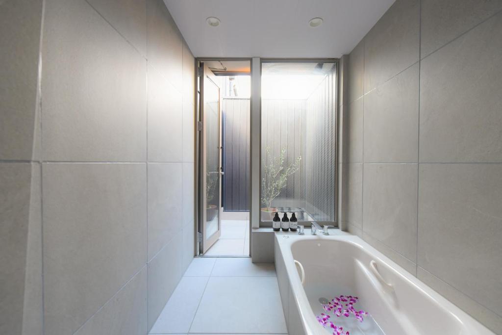 uma casa de banho branca com uma banheira e uma janela em ホテル SHUNJU Rooji 1日1組様限定 近隣駐車場有 em Quioto