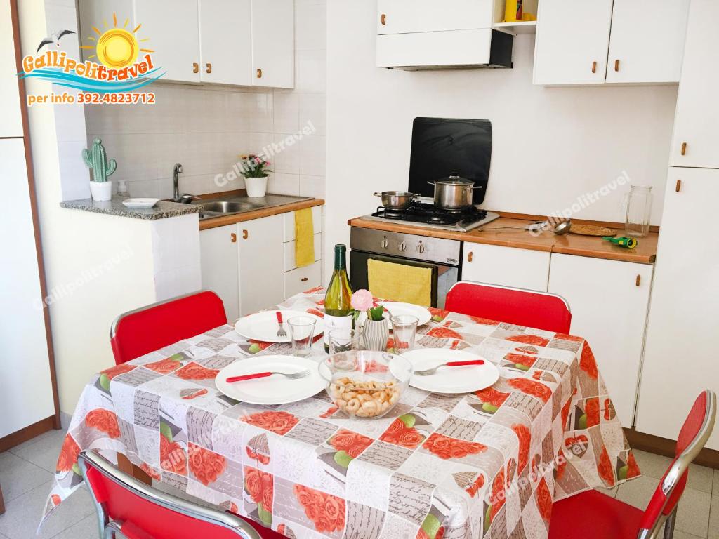 eine Küche mit einem Tisch und einem Tischtuch darauf in der Unterkunft Bilocale Baia Verde Gallipolitravel in Gallipoli