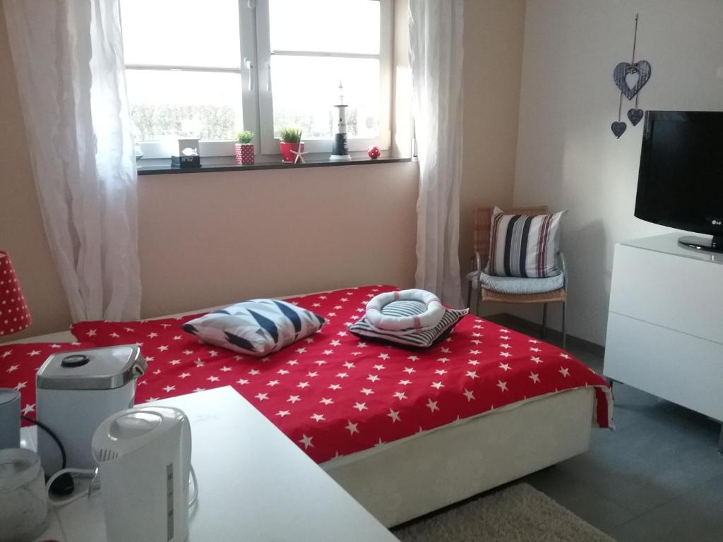 um pequeno quarto com uma cama vermelha e uma televisão em Privatzimmer Essy in RE em Recklinghausen