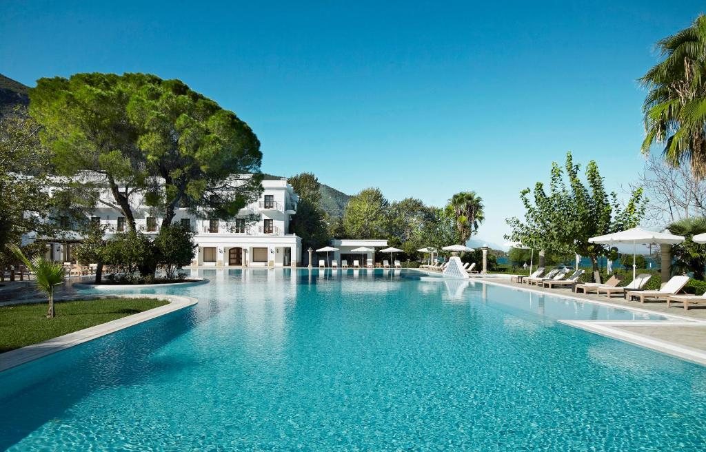 a large swimming pool with chairs and a fountain at Mitsis Galini in Kamena Vourla