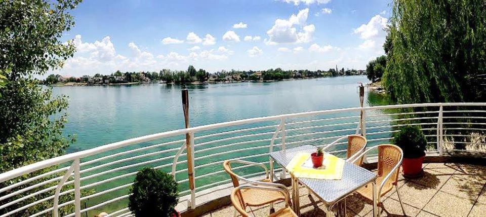 una mesa y sillas en un balcón con vistas al río en Hotel Zátoka, en Senec