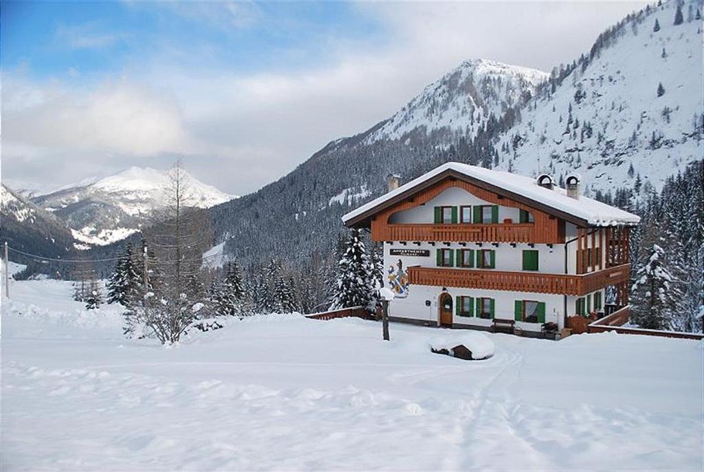 uma casa na neve com montanhas ao fundo em Appartamento N. 1 em Livinallongo del Col di Lana