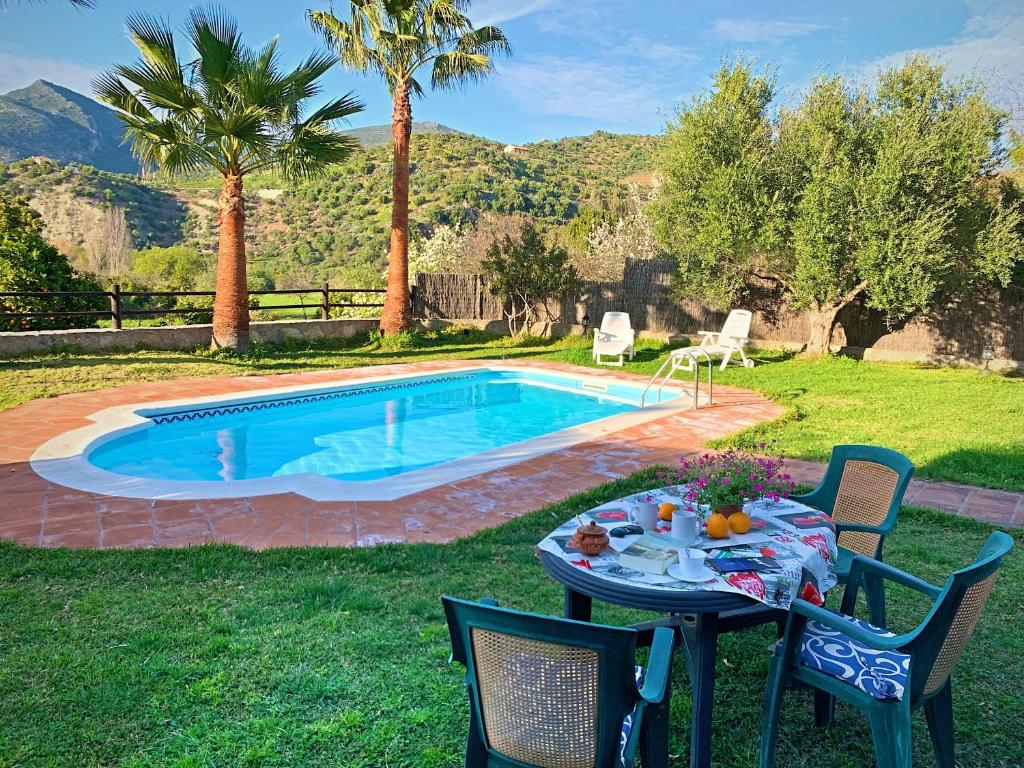 - une table et des chaises à côté de la piscine dans l'établissement Acogedora casa rural en Zahara de la Sierra, à Zahara de la Sierra