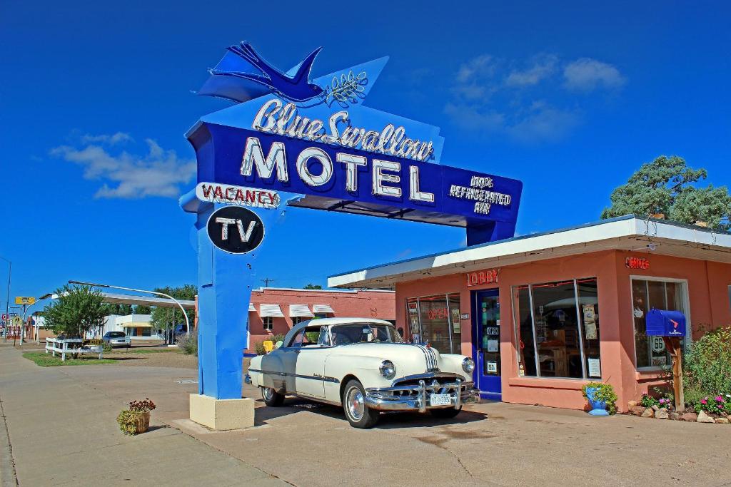 une vieille voiture est garée devant un motel dans l'établissement Blue Swallow Motel, à Tucumcari