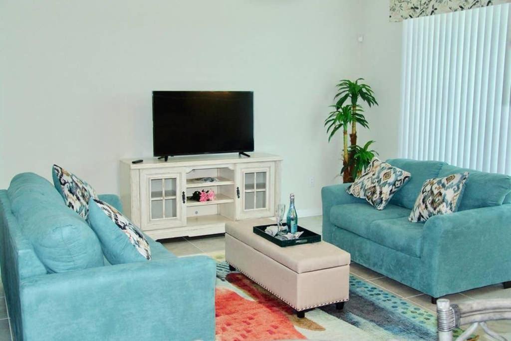 uma sala de estar com dois sofás azuis e uma televisão em Amazing Thematic 2BR with Waterpark em Kissimmee