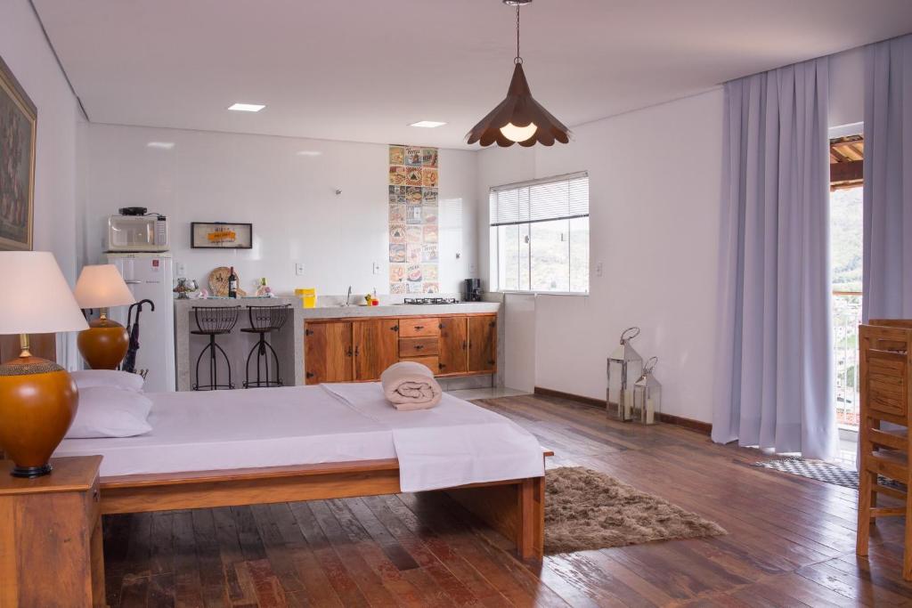 een slaapkamer met een groot bed en een keuken bij Loft Sopro da Serra in São João del Rei