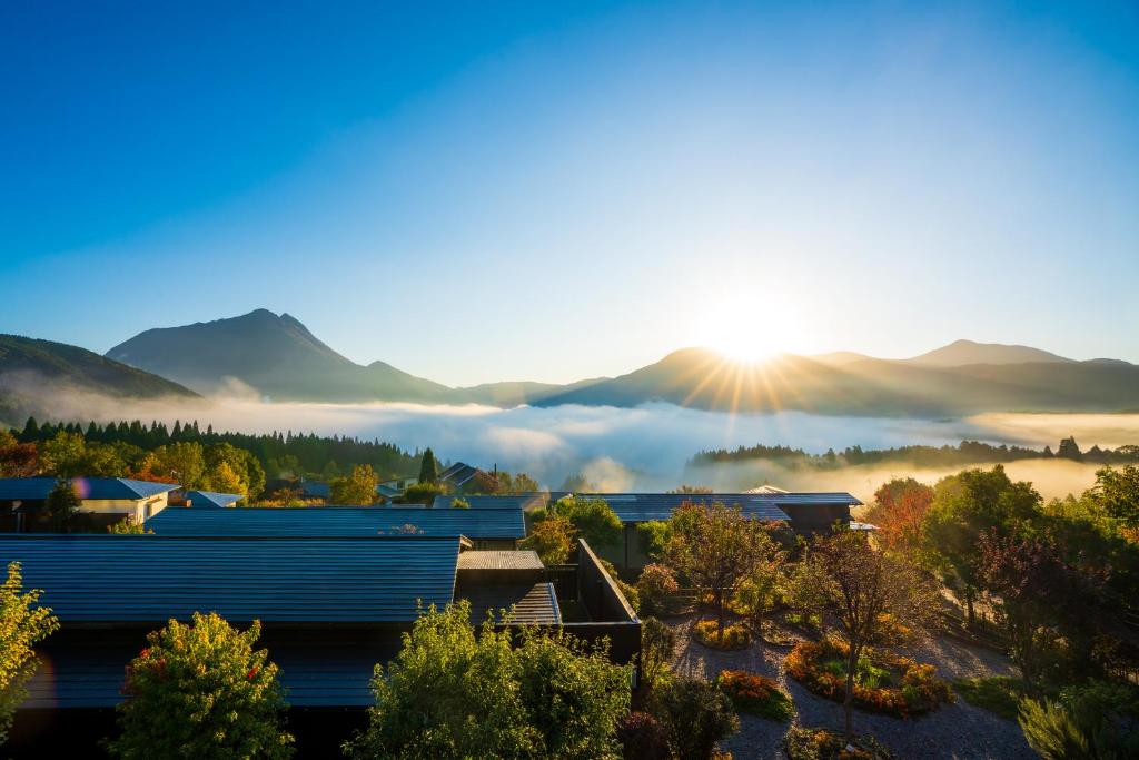 a view of a town with the sun rising over the mountains at Yufuin Hanayoshi in Yufu