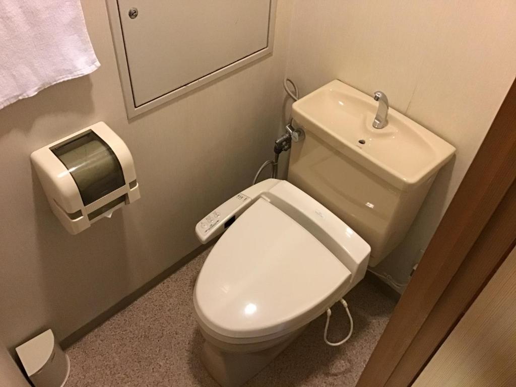 a bathroom with a white toilet and a paper dispenser at Kyonoyado Kagihei in Kyoto