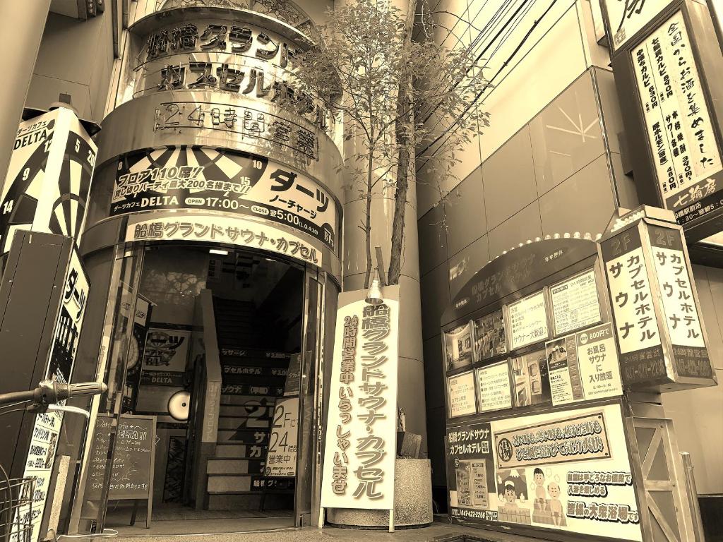 un magasin à l'avant d'un bâtiment avec des panneaux. dans l'établissement Funabashi Grand Sauna and Capsule Hotel, à Funabashi