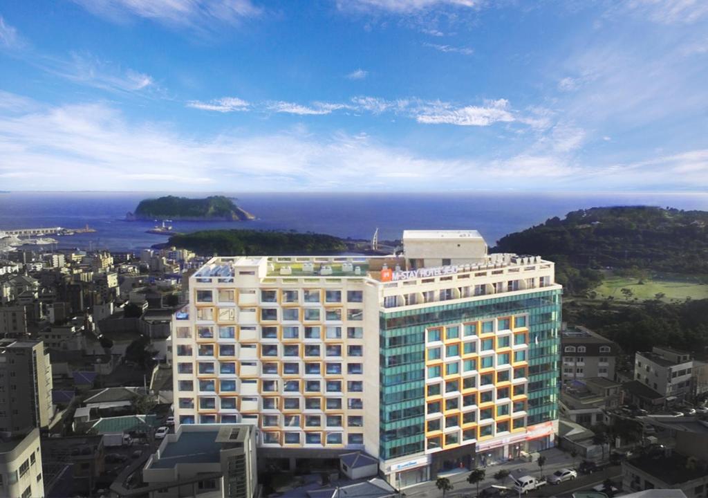 a tall building with the ocean in the background at Mstay Hotel in Seogwipo