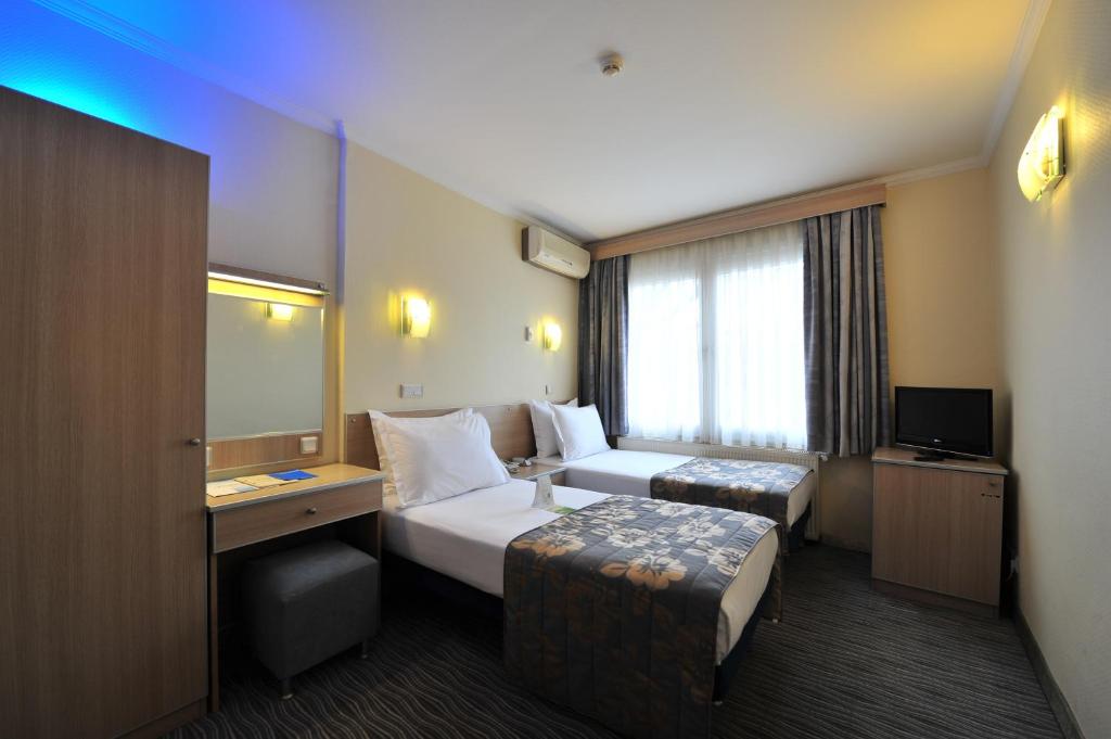 イスタンブールにあるホテル オリンピヤットのベッドとデスクが備わるホテルルームです。