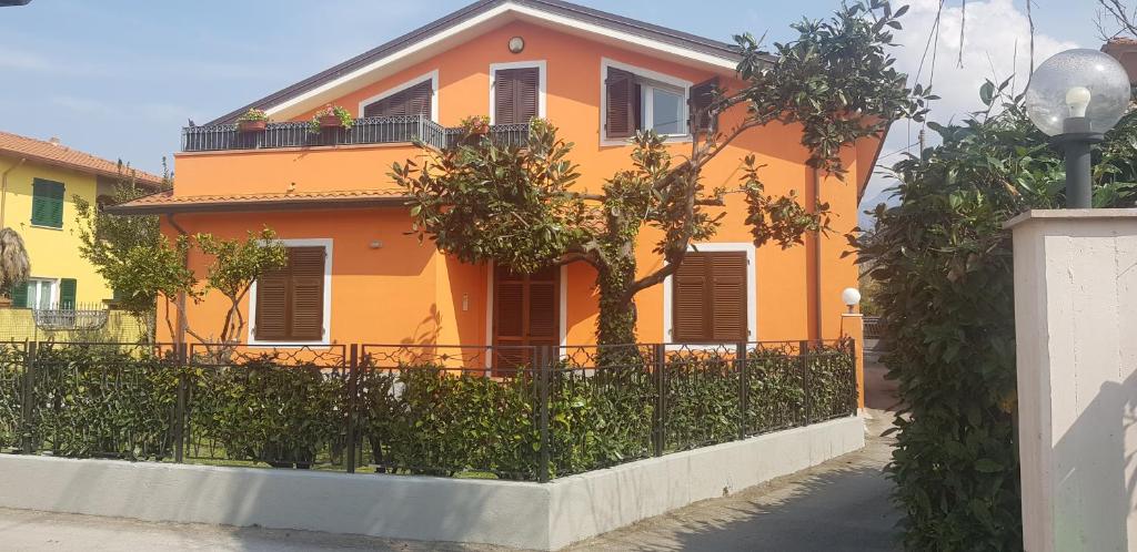 una casa naranja con una valla delante de ella en New Life, en Carrara