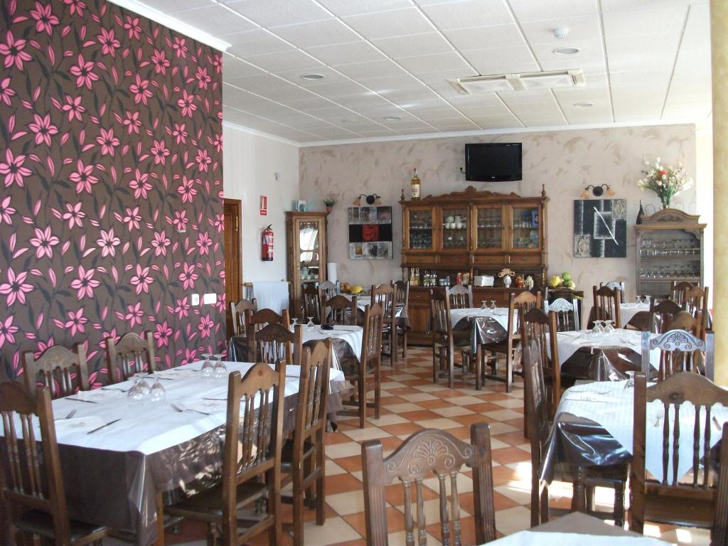 um restaurante com mesas e cadeiras e uma parede floral em Hostal Cabañas em Carboneras de Guadazaón