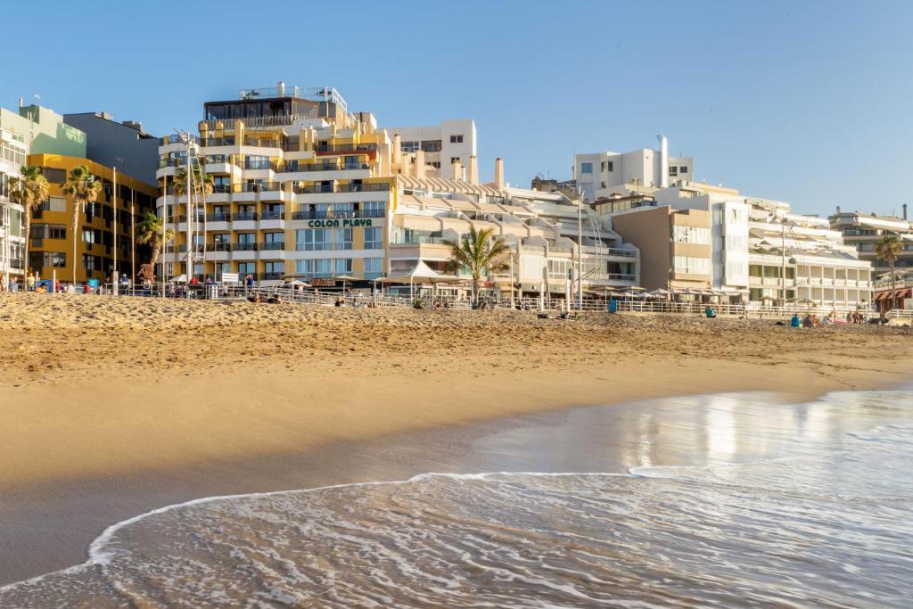 uma vista para uma praia com edifícios ao fundo em Apartamentos Colón Playa em Las Palmas de Gran Canaria