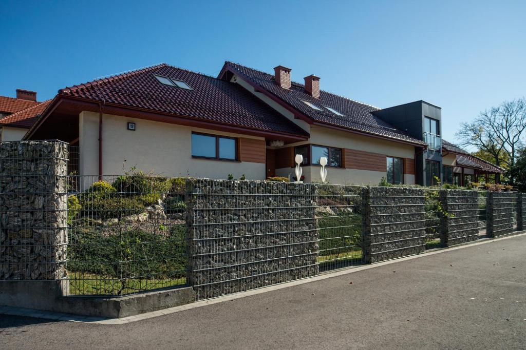 ein Haus mit einem Zaun davor in der Unterkunft Natura Villa Spa in Węgrzce