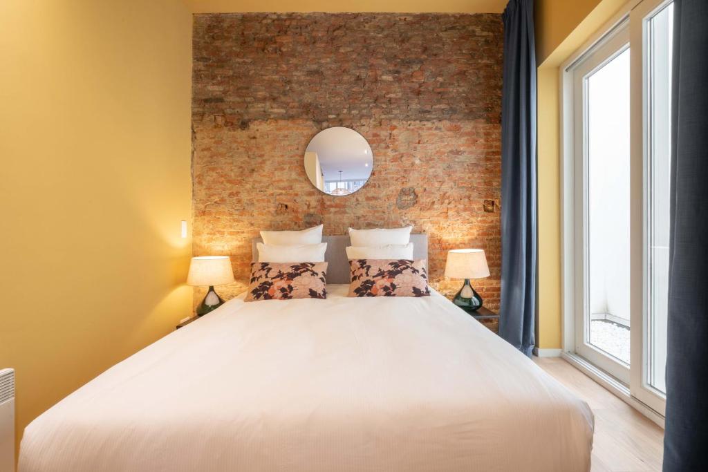 a bedroom with a large white bed with a brick wall at The Red Monkey in Antwerp