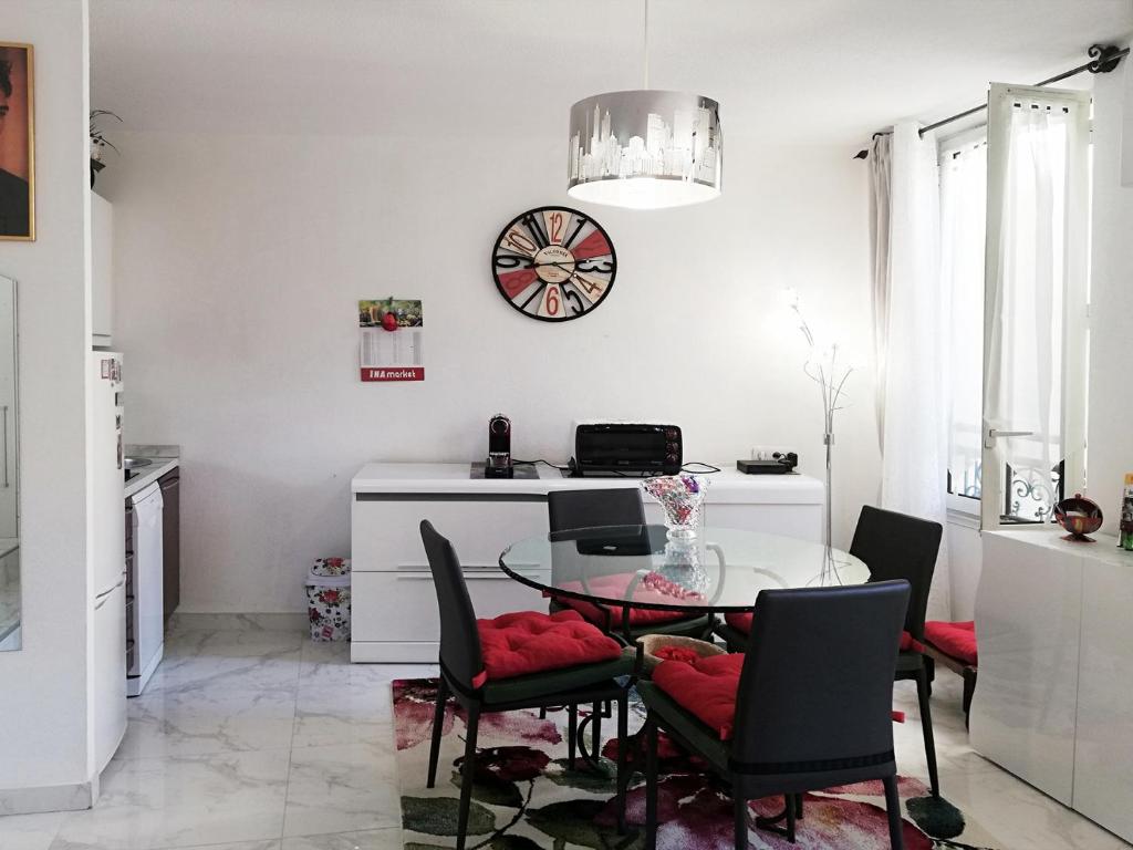 a dining room with a table and chairs and a clock at Cannes 3 min from Congress Palace, Croisette, Beaches in Cannes