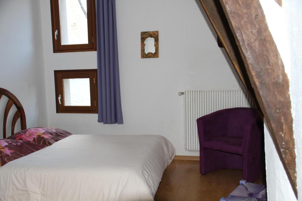 a bedroom with a bed and a purple chair at Hôtel Auberge du Combaïre in Laguiole