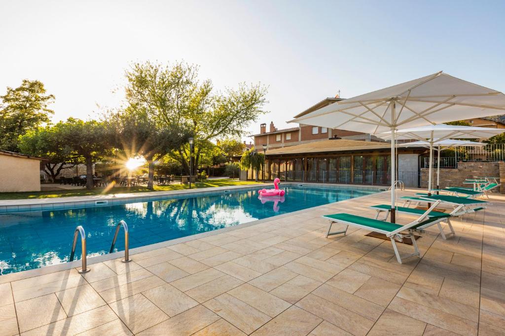 einen Pool mit Liegestühlen und einem Sonnenschirm in der Unterkunft Catignano Hotel Ristorante in Gubbio