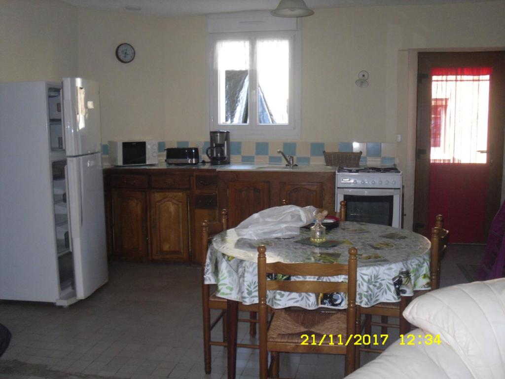uma cozinha com uma mesa e uma cozinha com um frigorífico em Maison - Chambre d’hôte située au cœur d Asfeld em Asfeld