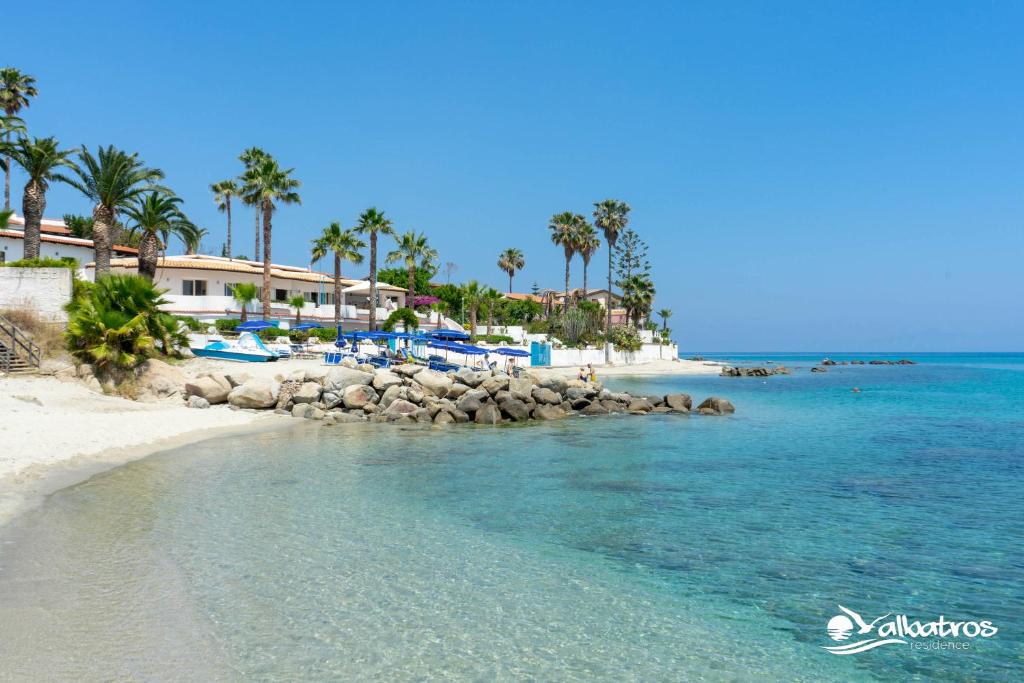 una spiaggia con acqua blu e palme e un resort di Residence Albatros a Briatico