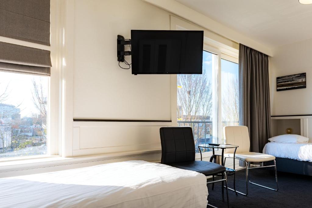 a hotel room with a bed and a flat screen tv at Stad &amp; Strandhotel Elisabeth in Vlissingen